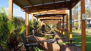 A covered outdoor seating area with wicker furniture and a pergola structure.