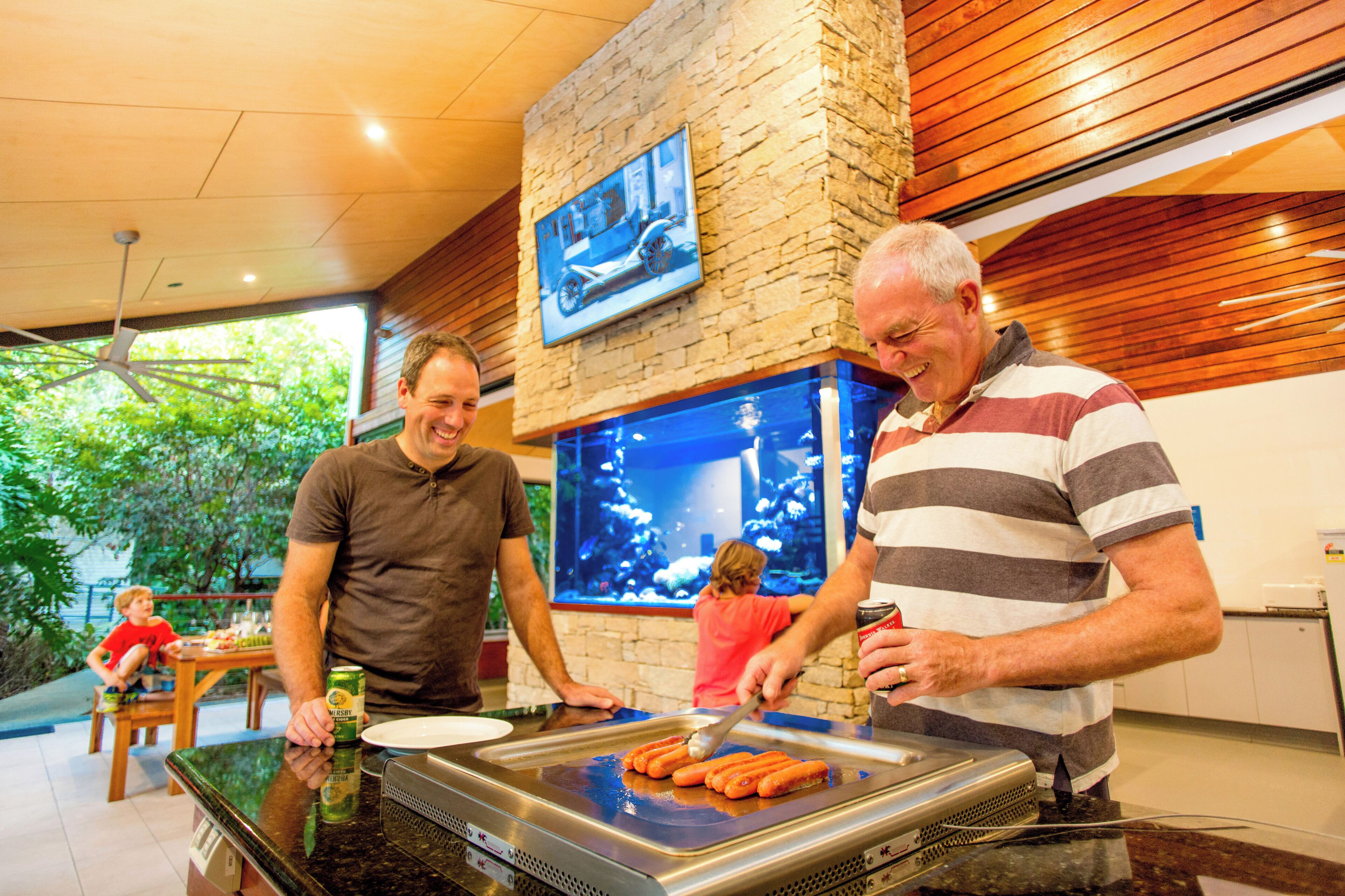 A restaurant with a grill, a large fish tank, and a stone wall.