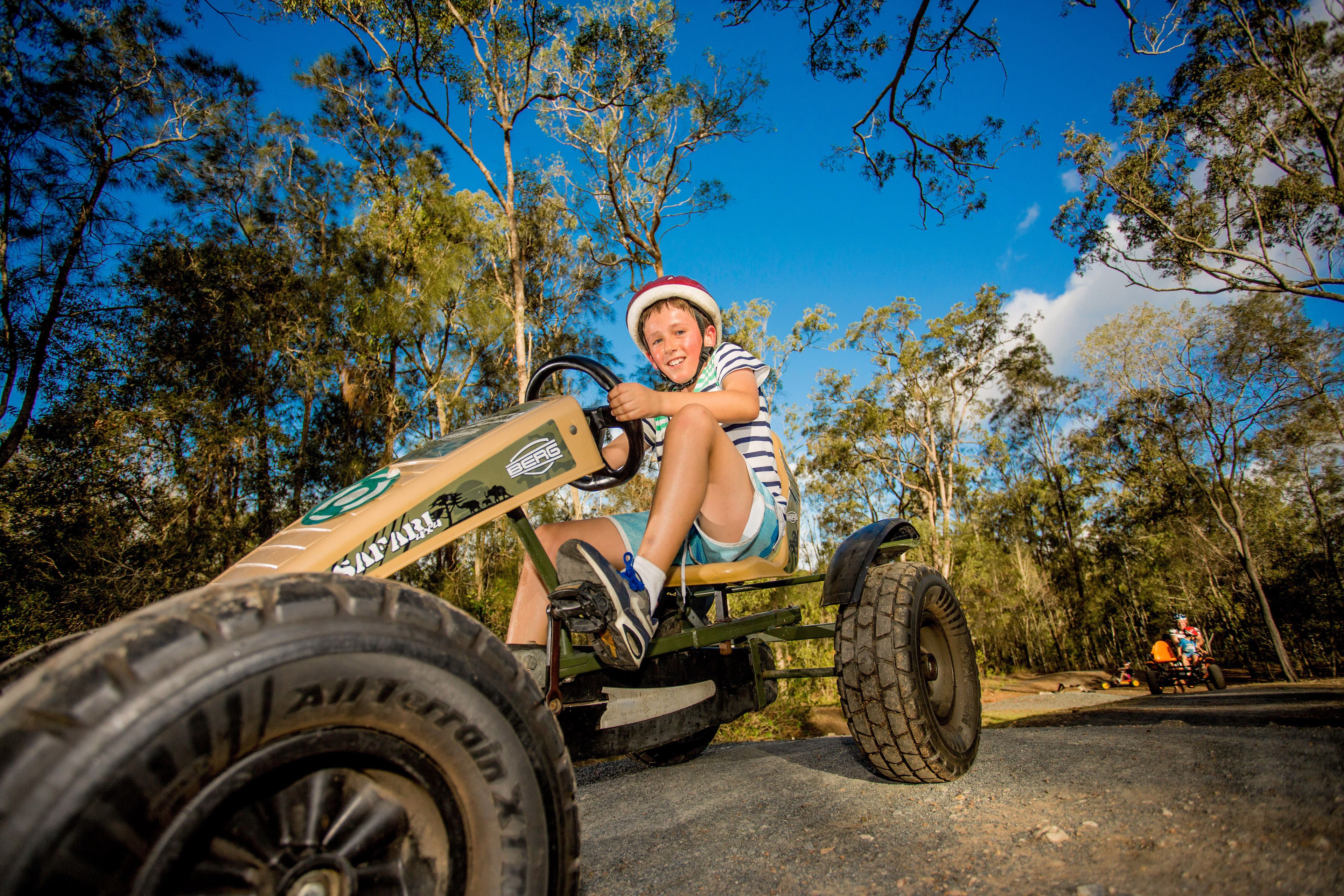 A child on a small off-road vehicle in a wooded area.