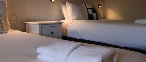 A hotel room with a large bed, a bedside table, and two wall-mounted light fixtures.