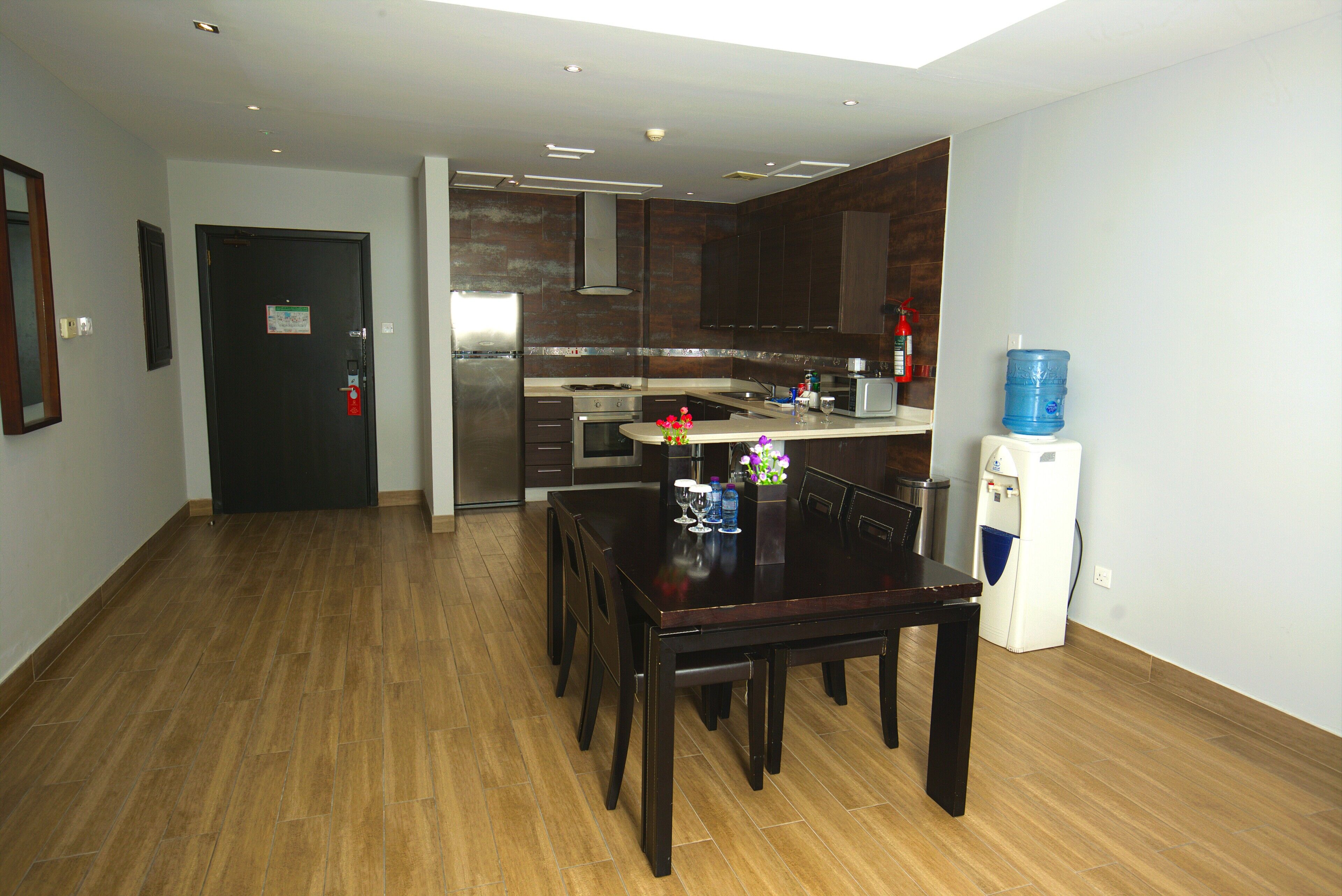 A modern kitchen with dark wooden cabinets, a built-in oven, and a water dispenser.