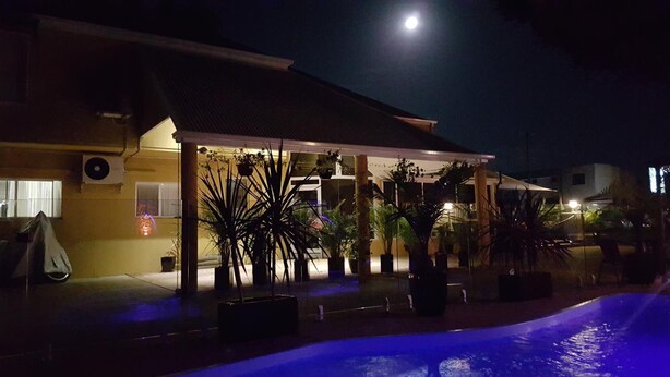 Un hotel con un espacio exterior techado, piscina y plantas en macetas.