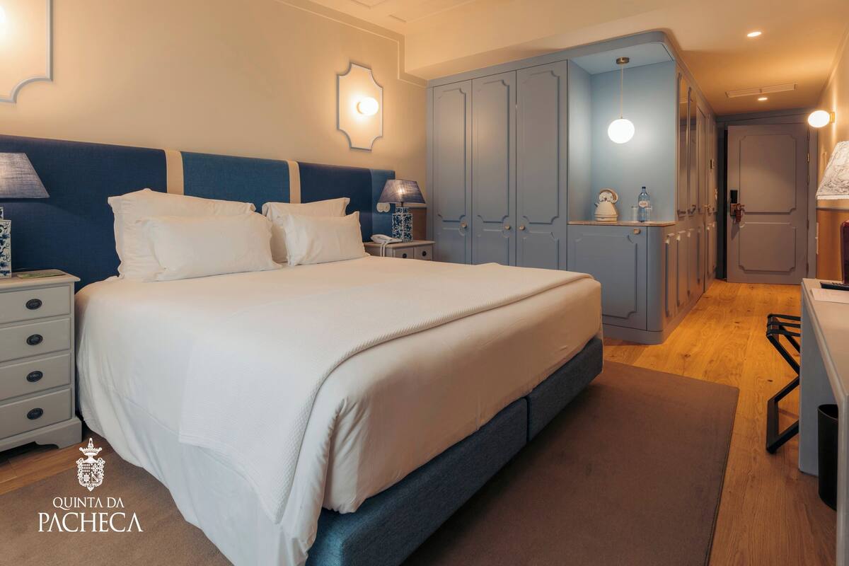 Ein Schlafzimmer mit einem großen Bett, Nachttischen, einem Kleiderschrank und einem Schreibtisch mit Stuhl.