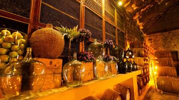Una bodega con barricas de madera, botellas de vidrio y cestas de mimbre.