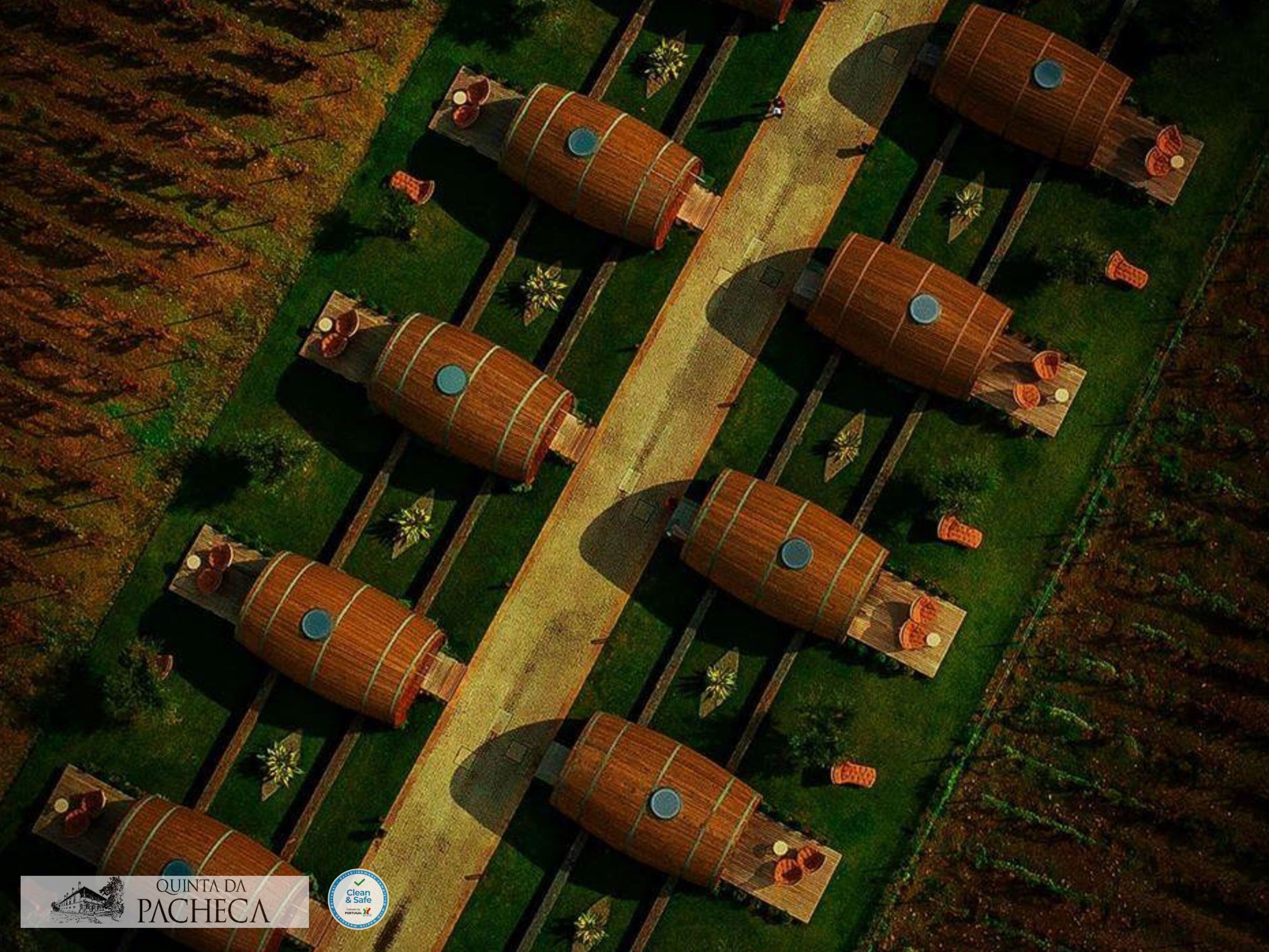 An aerial view of a property with multiple wooden barrel-shaped structures arranged in a grid pattern, surrounded by green lawns and pathways.
