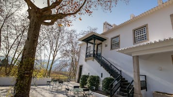 A courtyard with outdoor seating, a staircase, and a building with a white facade.