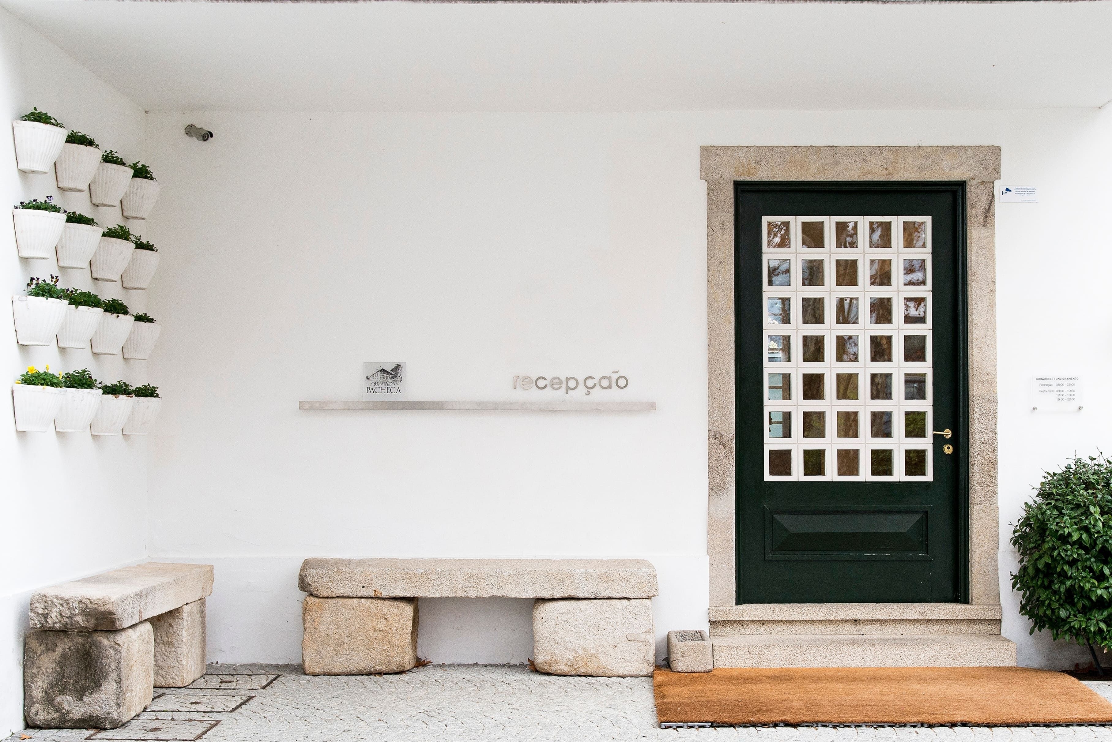 A clean, minimalist entrance with a green door, a bench, and potted plants.