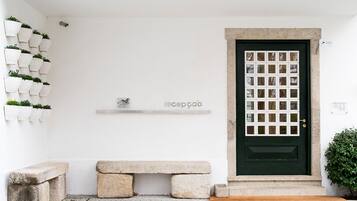 A clean, minimalist entrance with a green door, a bench, and potted plants.
