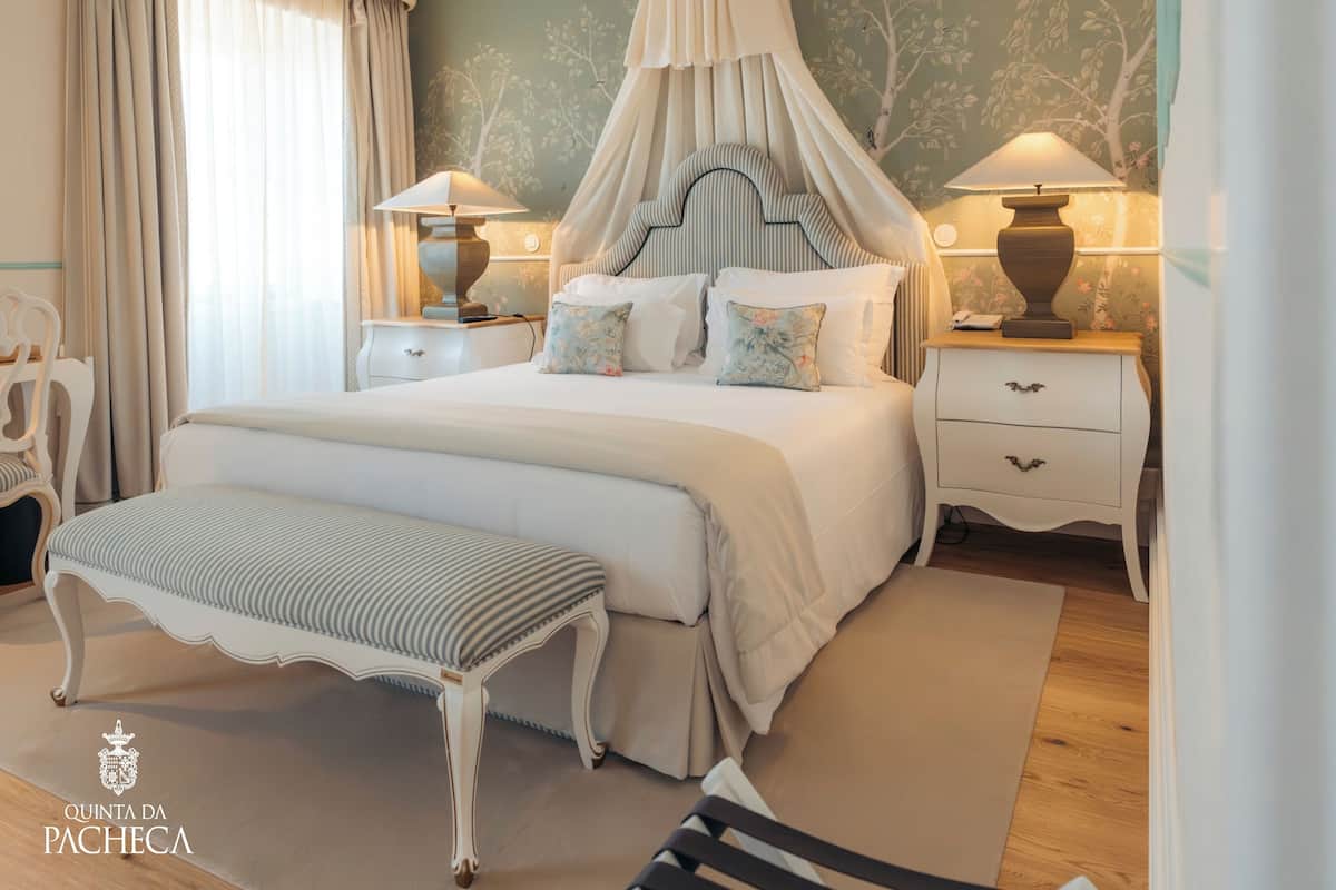 Ein geräumiges Schlafzimmer mit einem großen Bett, zwei Nachttischen, einer Bank und einem Baldachin.