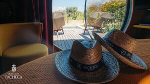 A room with a view of a pool and outdoor seating, featuring woven hats and a logo for Pacheca Group. - The Wine House Hotel - Quinta da Pacheca (Lamego)