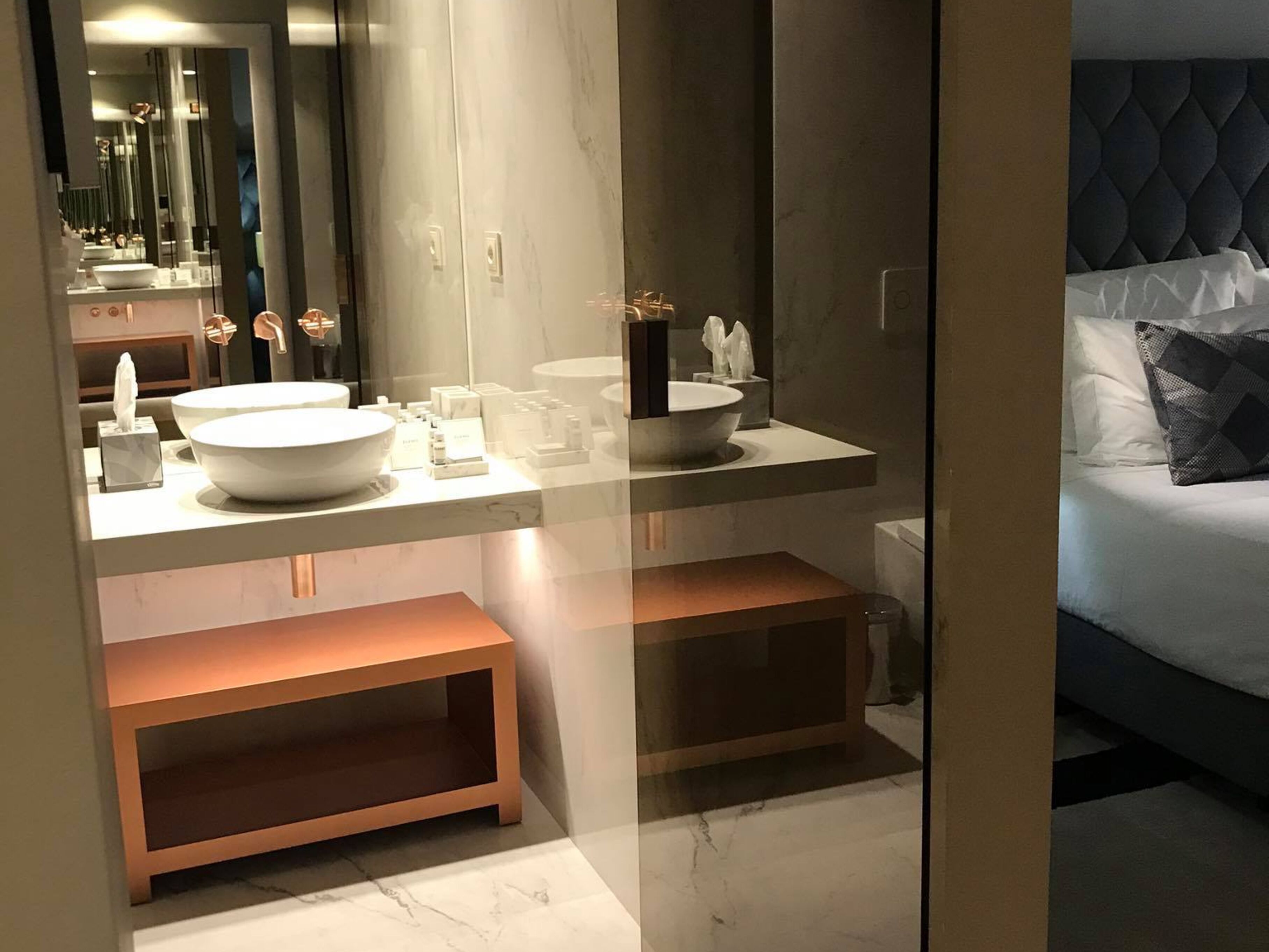 Une salle de bain moderne avec un grand miroir, un lavabo blanc et un meuble-vasque avec espace de rangement.