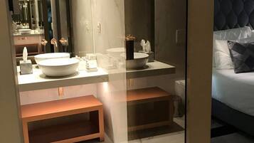 Une salle de bain moderne avec un grand miroir, un lavabo blanc et un meuble-vasque avec espace de rangement.