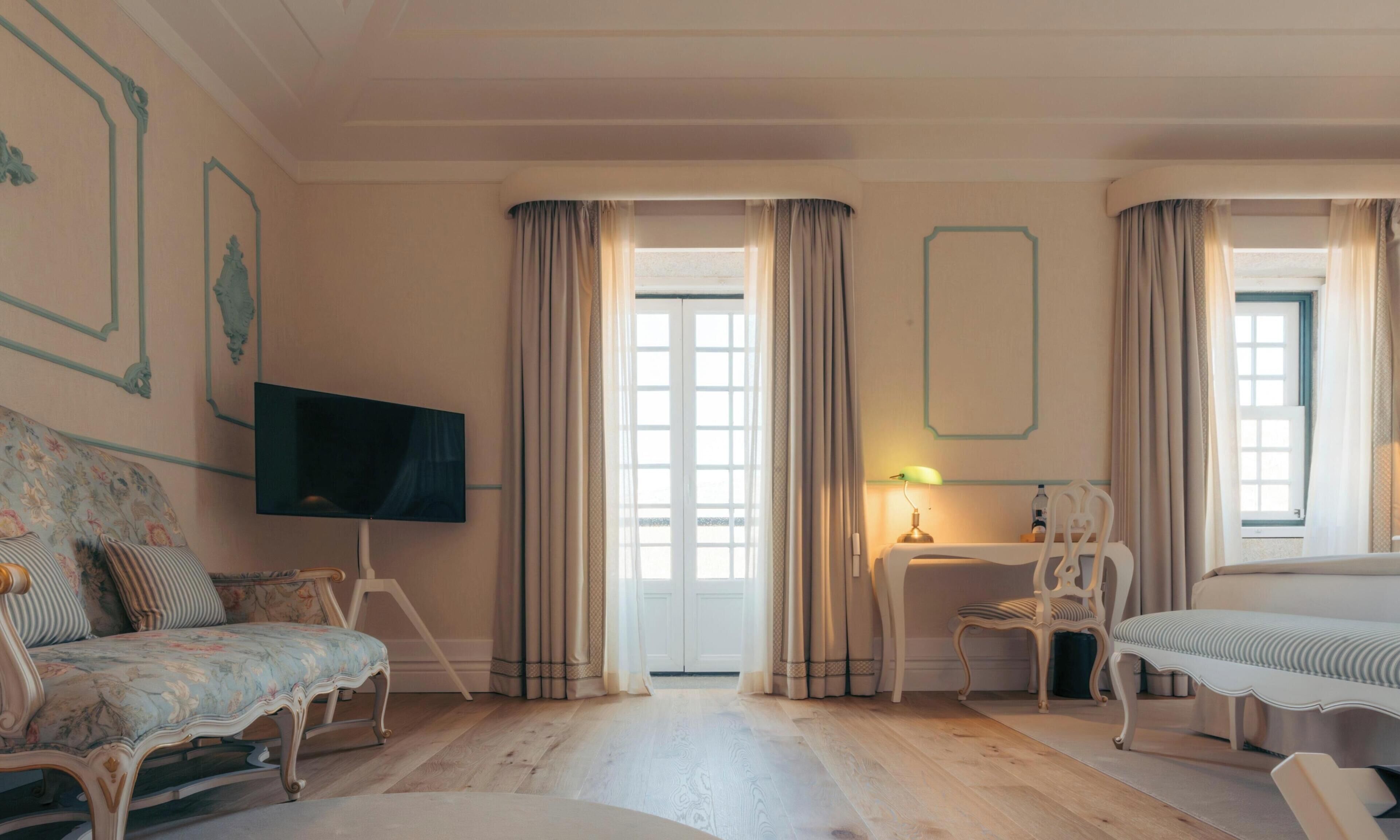 Una habitación amplia con una cama grande, un sofá, un televisor y un escritorio con lámpara.