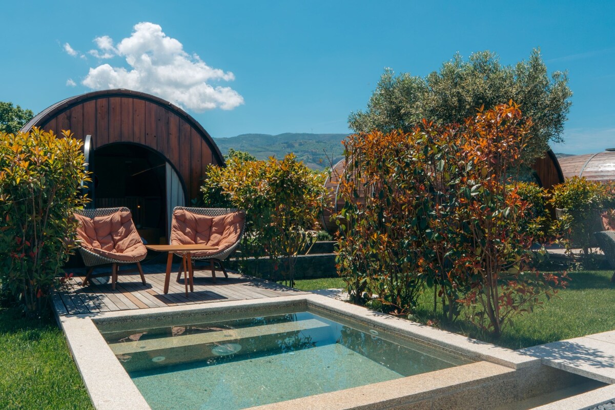 A pool area with two wicker chairs, a wooden structure, and a view of hills.