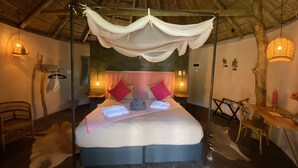 Une chambre avec un lit sous un dais, un plafond en bois et une petite table avec une chaise.