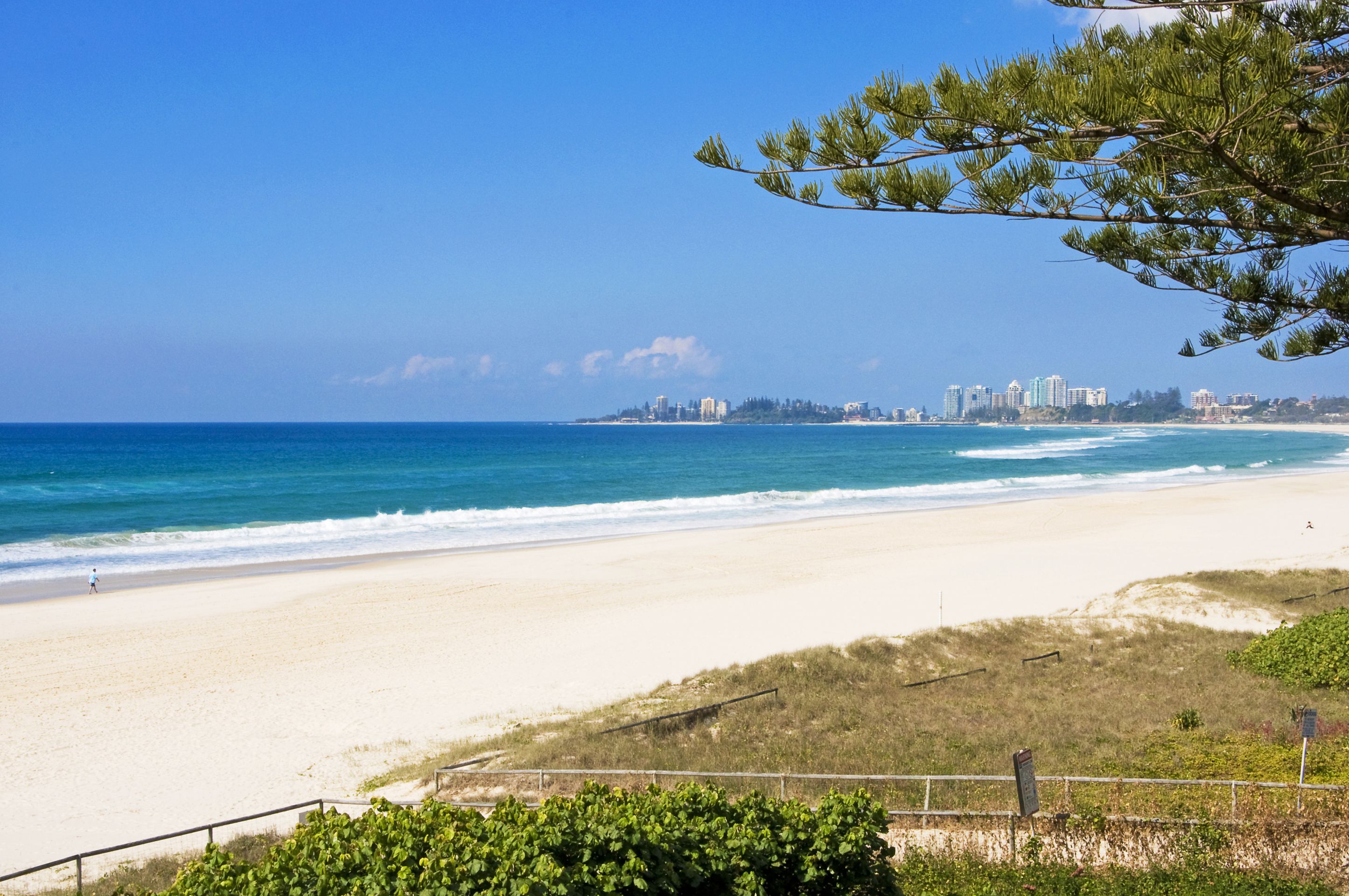 Una playa con vista despejada al océano y un horizonte urbano distante.