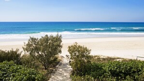 A beach with a clear path leading to the shore, surrounded by greenery. - Oceanside Resort (Bilinga)