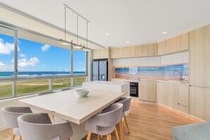 A modern kitchen with a large island, wooden cabinets, and a view of the ocean. - Oceanside Resort (Bilinga)