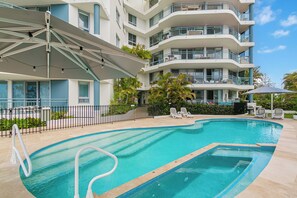Una piscina al aire libre, sombrillas, sillones reclinables de piscina