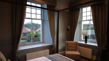 Une chambre d’hôtel avec un lit, une chaise, une lampe et des fenêtres avec des rideaux.