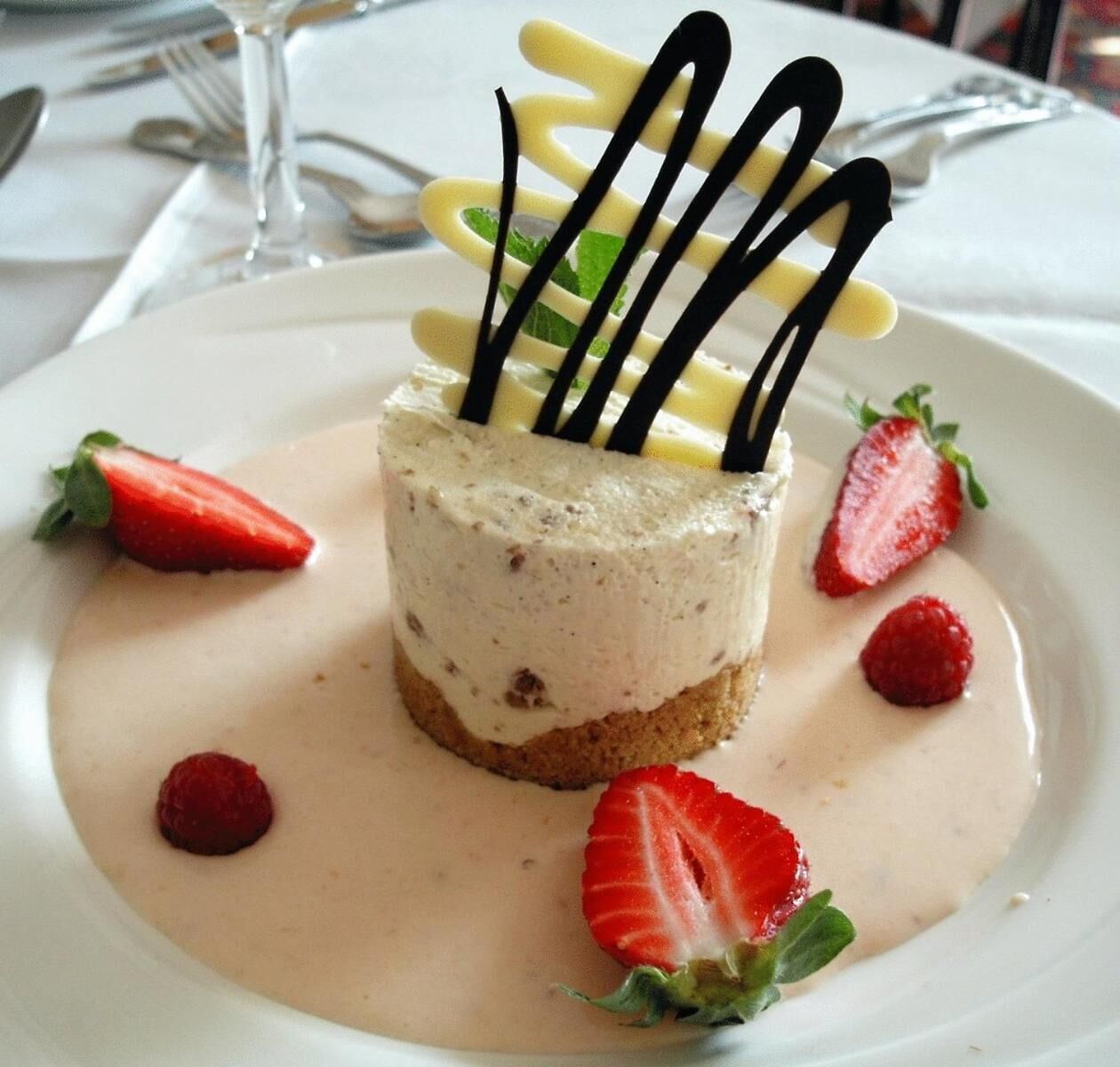 Postre amb freses i una salsa cremosa sobre un plat blanc.