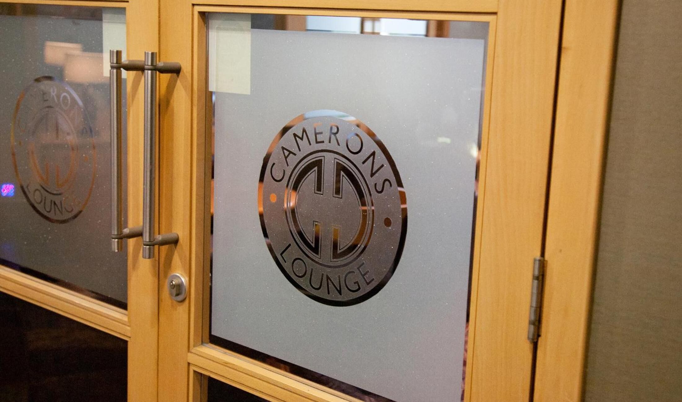 A door with a frosted glass panel featuring the text "CAMERONS LOUNGE".