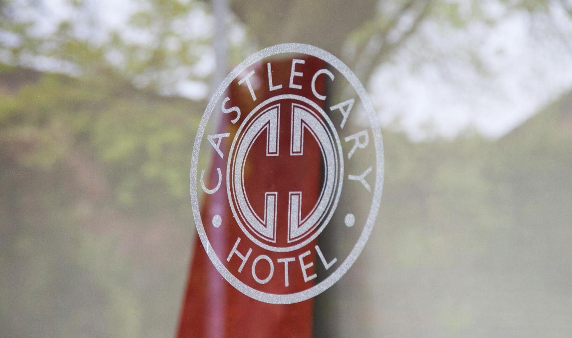 A circular logo with the text "CASTLECARRY HOTEL" and a central emblem.