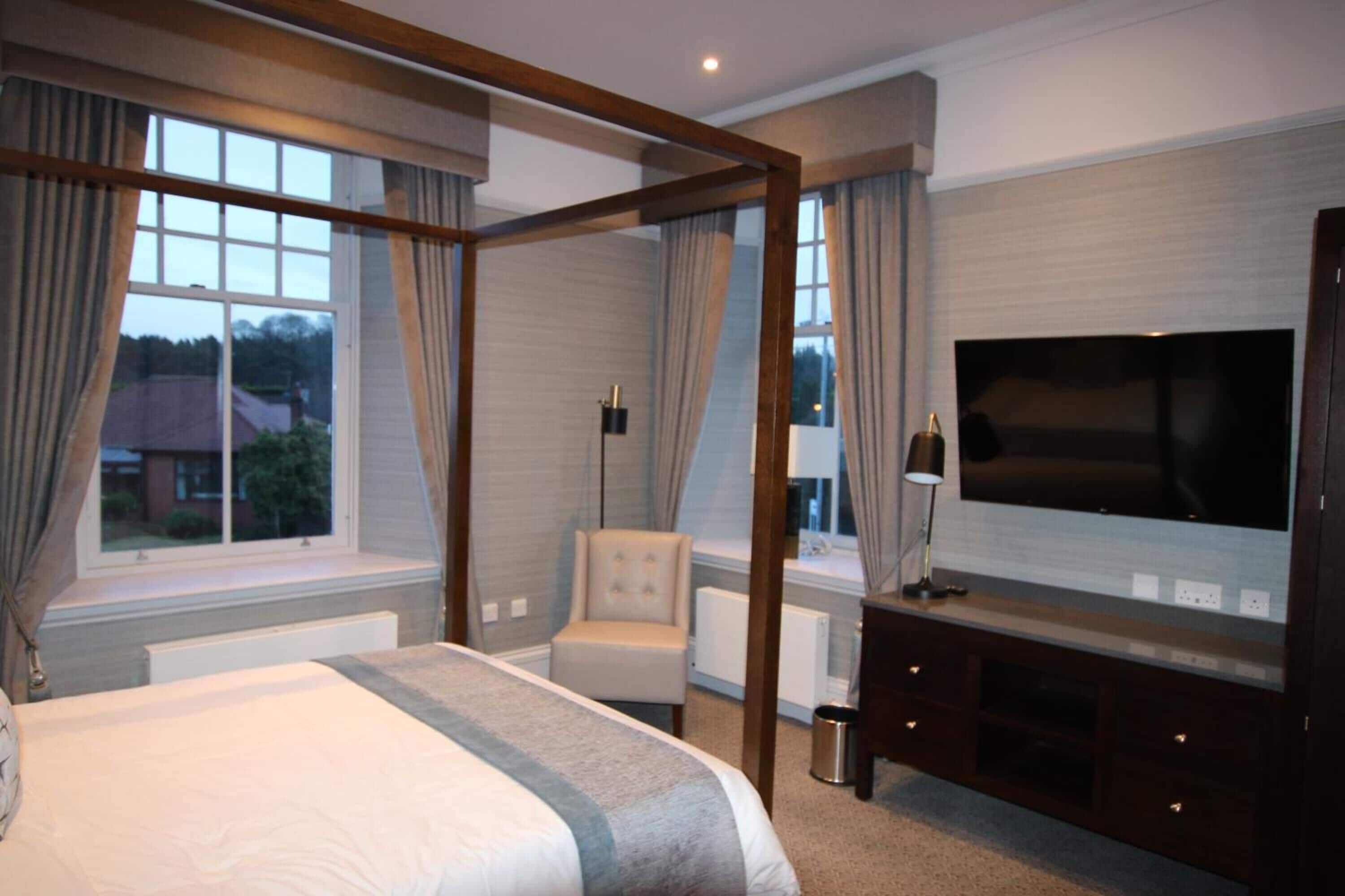 Ein Schlafzimmer mit Himmelbett, Fernseher, Stuhl und Blick ins Freie.