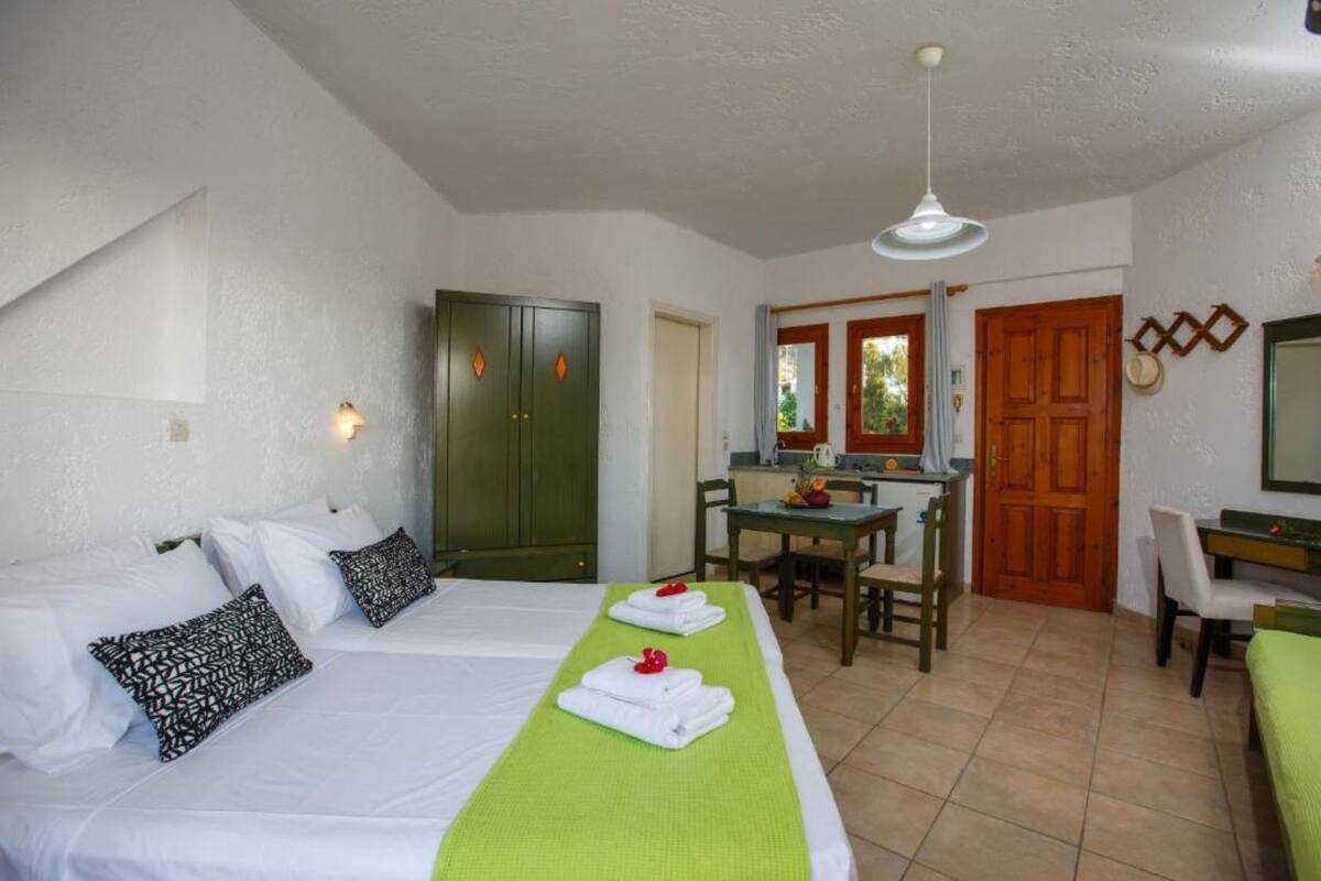 Een hotelkamer met twee bedden, een eethoek en een keuken.