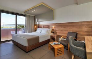 Habitación de hotel con una cama grande, un escritorio, una silla y vistas a la ciudad.
