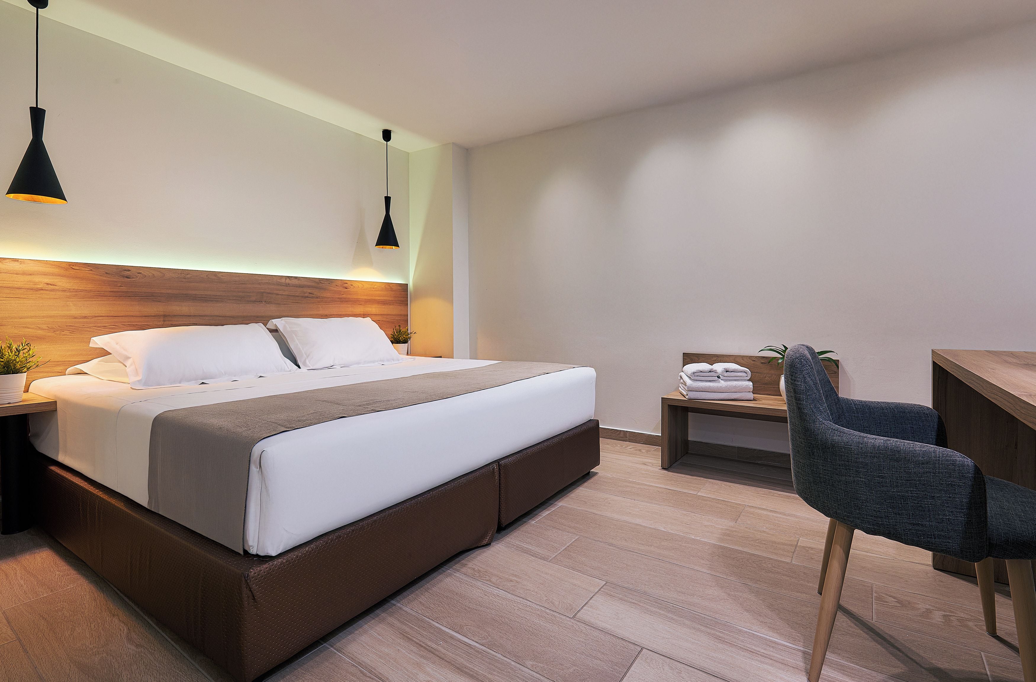 Une chambre d’hôtel moderne, dotée d’un grand lit, de tables de chevet, d’un bureau et d’une chaise.