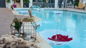 A poolside area with a decorative umbrella, a birdcage with plants, and a bench.