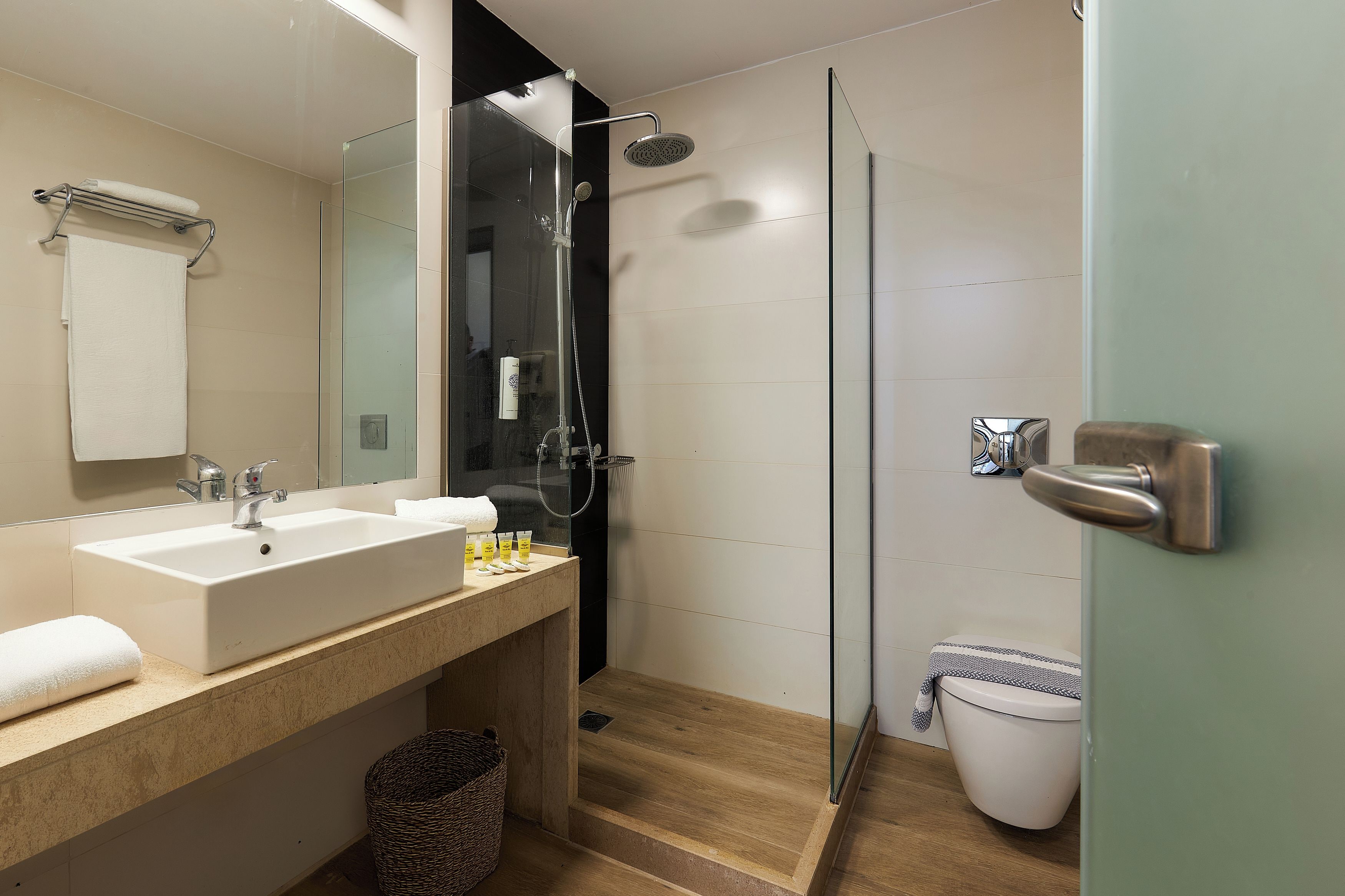Une salle de bain moderne avec une douche à parois de verre, un lavabo avec une serviette et des toilettes.