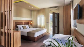 A modern hotel room with a large bed, wooden headboard, a bedside table, a TV, and a view of the outdoors.