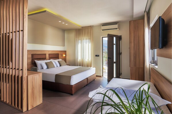 Quarto de hotel moderno com uma cama grande, cabeceira de madeira, mesa de cabeceira, televisão e vista para o exterior.