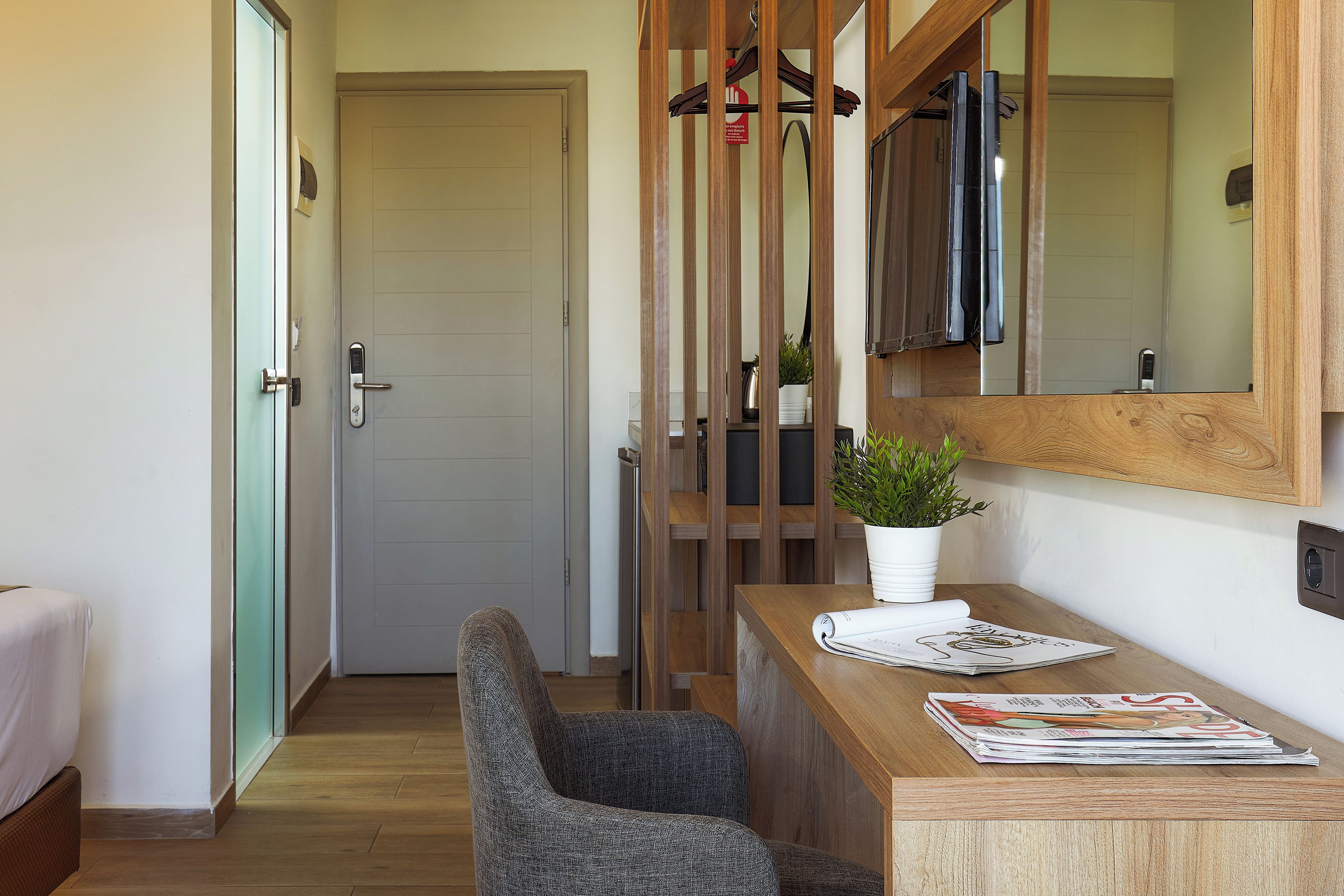 A room with a wooden desk, a chair, a potted plant, and a door.