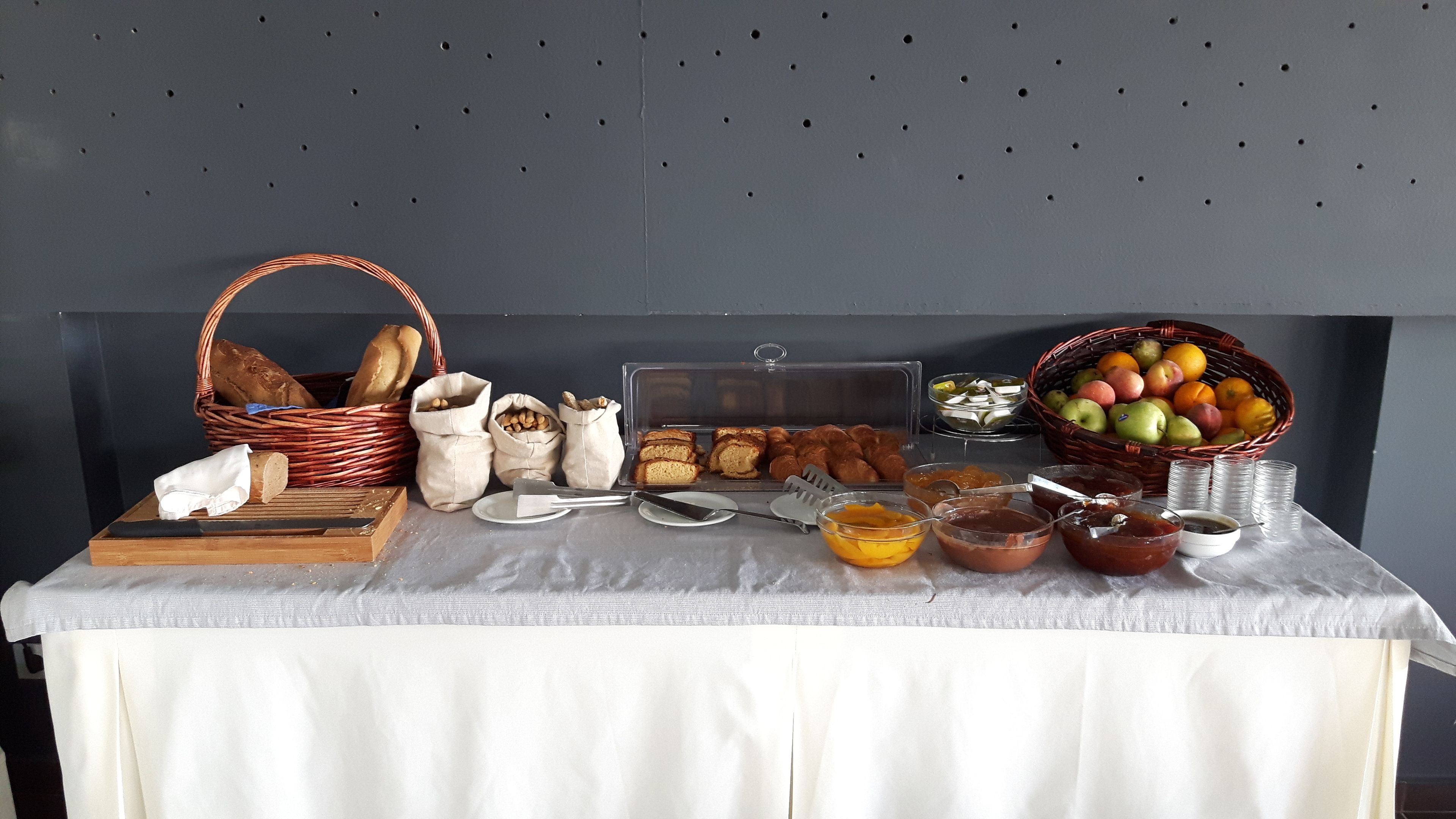 Una mesa de buffet con diversos alimentos, como pan, pasteles y frutas.