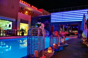 Uma área de piscina de hotel com lanternas decorativas e uma piscina bem iluminada.