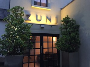 A building entrance with the sign 'ZUNI' illuminated above the door.