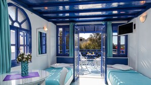 A room with two beds, a table with a vase, and a balcony with a table and chairs.
