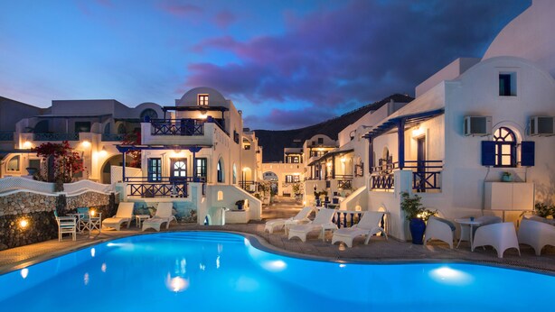 A resort with a swimming pool, white buildings, and outdoor seating areas.