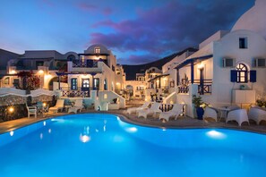A resort with a swimming pool, white buildings, and outdoor seating areas. - Samson's Village (Santorini)