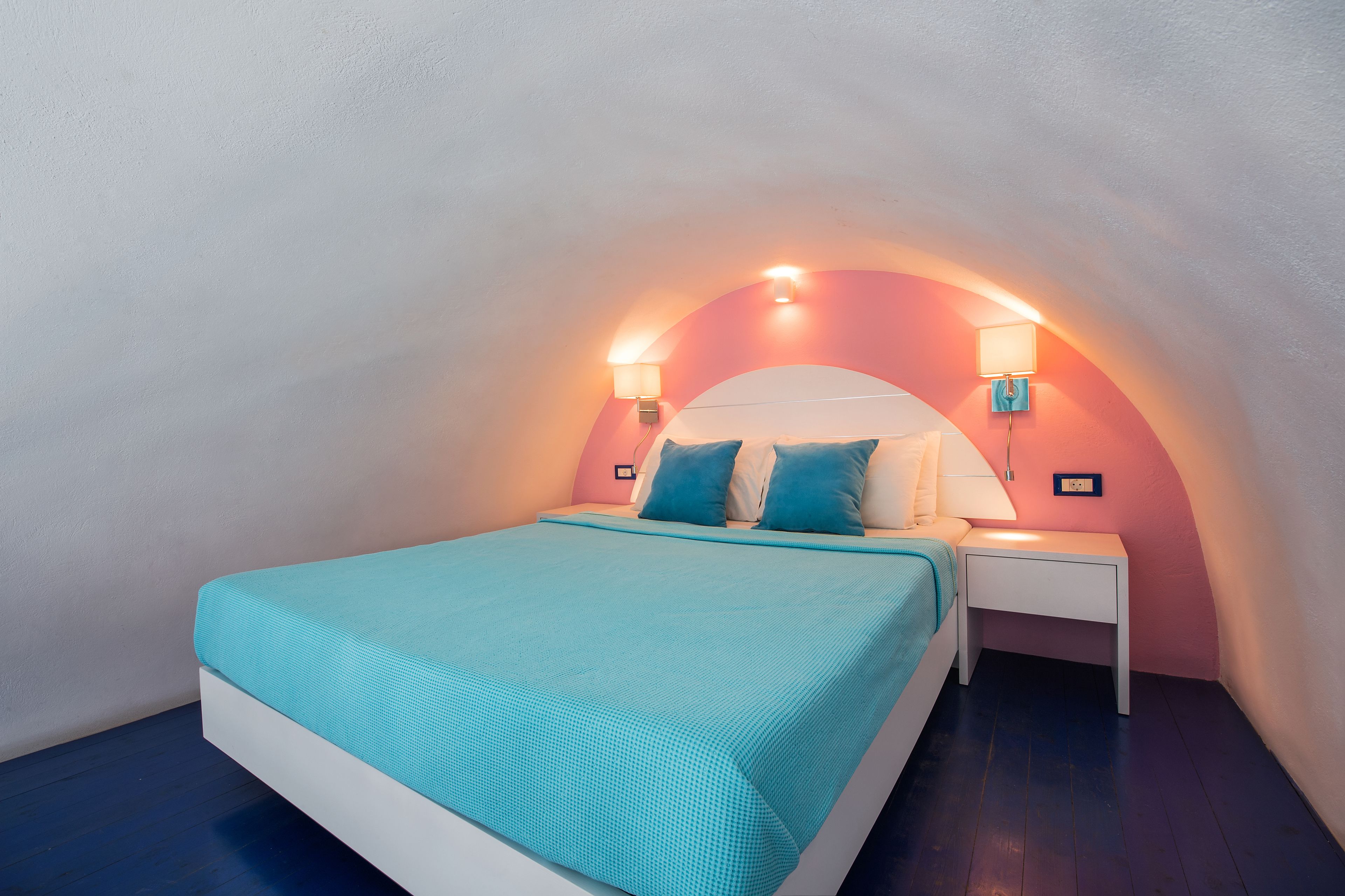 A bedroom with a bed, nightstands, and wall-mounted lamps.