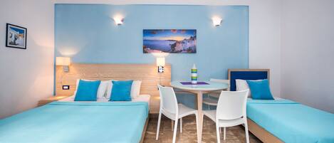 A hotel room with two beds, a dining table, and chairs.