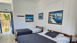 A hotel room with two beds, a ceiling fan, and artwork on the walls. - SartiVista (Sithonia)