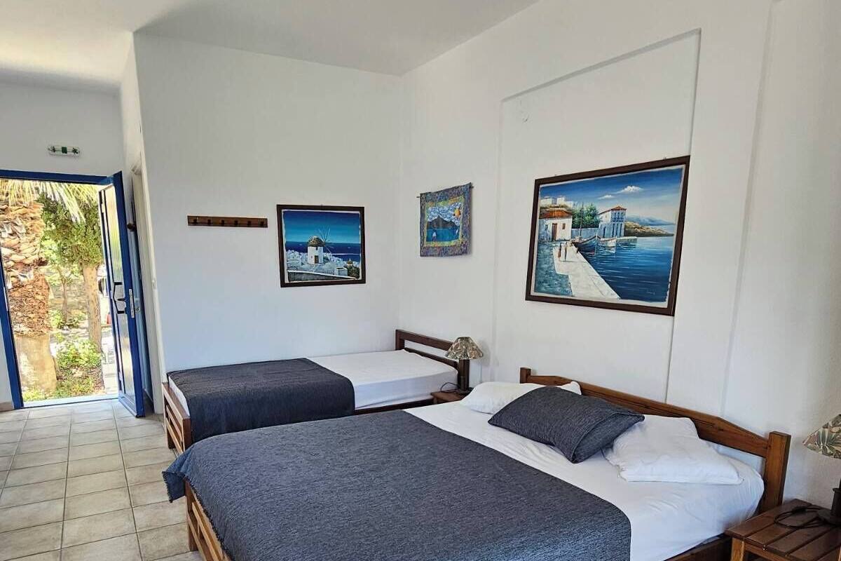 Ein Hotelzimmer mit zwei Betten, einem Deckenventilator und Bildern an den Wänden.
