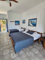 Una habitación de hotel con dos camas, un ventilador de techo y obras de arte en las paredes.