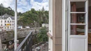 A balcony with a view of a town, a flag, and a building with a balcony. - Hôtel - Restaurant Victor Hugo (Vianden)