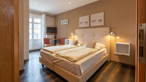 A hotel room with a large bed, a TV, a desk, and a chair. - Hôtel - Restaurant Victor Hugo (Vianden)