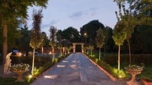 A pathway lined with trees and illuminated by street lamps, leading to a structure in the distance. - Villa Horti della Fasanara (Ferrara)